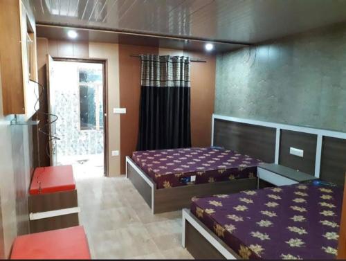a bedroom with two beds and a door to a room at Kuber Palace Badrinath in Badrīnāth
