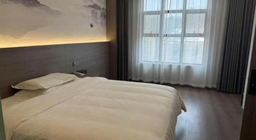 a bedroom with a large white bed with a window at GreenTree Alliance Anhui Hefei South Passenger Station South High Speed Railway Station Hotel in Hefei