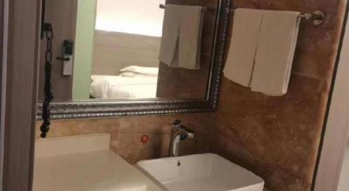a bathroom with a mirror and a sink and a tub at GreenTree Alliance Anhui Hefei South Passenger Station South High Speed Railway Station Hotel in Hefei