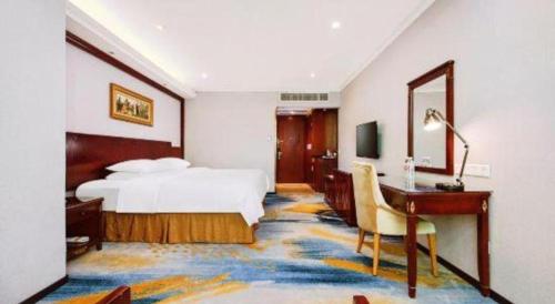 a hotel room with a bed and a desk and a bedroom at Vienna 3 Best Hotel Dongguan Fenggang Yongsheng Street in Tiantangwei