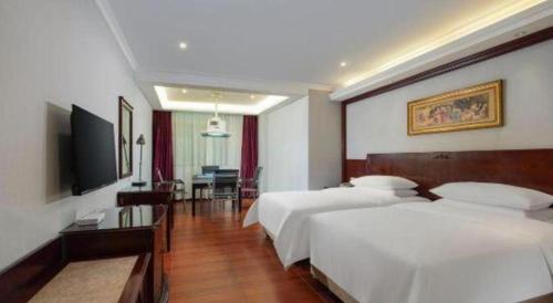 a hotel room with two beds and a television at Vienna 3 Best Hotel Dongguan Fenggang Yongsheng Street in Tiantangwei