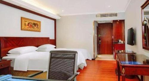 a bedroom with two beds and a desk and a television at Vienna 3 Best Hotel Dongguan Fenggang Yongsheng Street in Tiantangwei