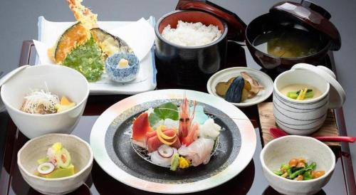 a table with plates of food and bowls of food at Hotel AreaOne Banjinmisaki in Kashiwazaki