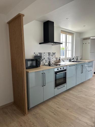 une cuisine avec des armoires blanches et un four à plaques de cuisson dans l'établissement Lenvolee paysanne, à Vauchamps