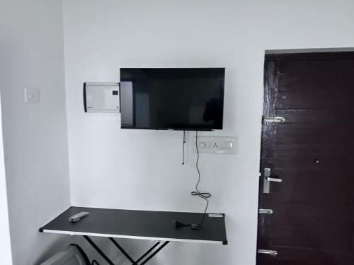 une pièce avec une télévision sur un mur avec une table dans l'établissement Golden Heights Apartments, à Trivandrum