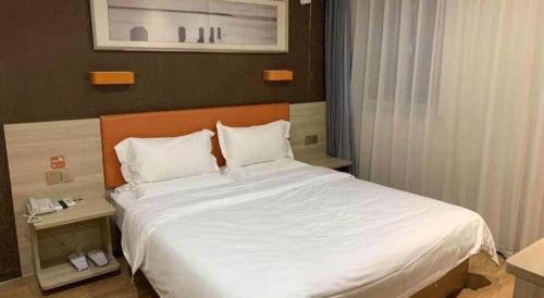 a bedroom with a large bed with white sheets at 7 Days Premium Yancheng Dafeng Zhongjiao Meilu City in Yancheng
