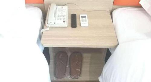 a bed with a nightstand with a phone and a phone at 7 Days Premium Yancheng Dafeng Zhongjiao Meilu City in Yancheng