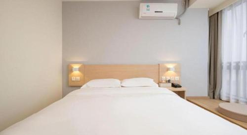 a bedroom with a large white bed and a window at 7 Days Inn Suzhou Mudu Ancient Town Kaima Auto Market in Suzhou