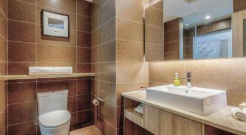 a bathroom with a sink and a toilet and a mirror at Atour Hotel Xi'an High Tech Dazhai Road in Xi'an