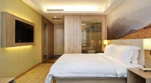 a bedroom with a large white bed and a tv at Atour Hotel Xi'an High Tech Dazhai Road in Xi'an