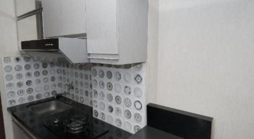 a small kitchen with a sink and white cabinets at OYO Living 3091 Apt The Suites Metro By Ananda in Bandung