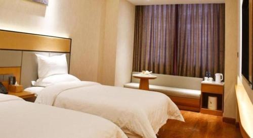 a hotel room with two beds and a window at GreenTree Inn Geermu Walking Street Business Hotel in Golmud