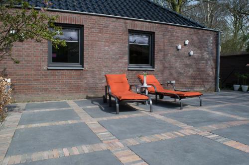 two orange chairs sitting in front of a brick building at Bed & breakfast bösdael in Reuver