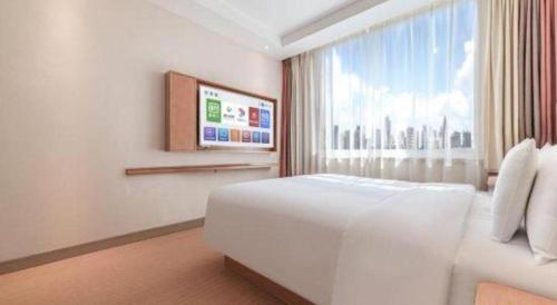 a bedroom with a large white bed and a window at GreenTree Inn Geermu Walking Street Business Hotel in Golmud