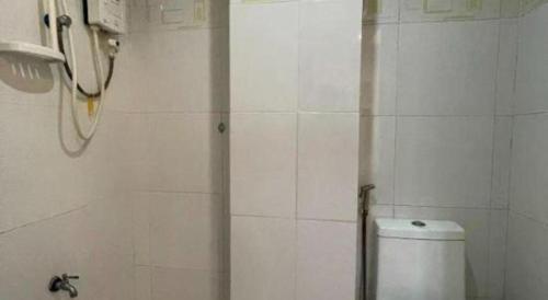 a white tiled bathroom with a toilet and a phone at Pilot Hotel in Alaminos