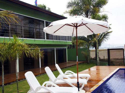 a group of chairs and an umbrella next to a pool at Posada Sueños De Verano in Florianópolis