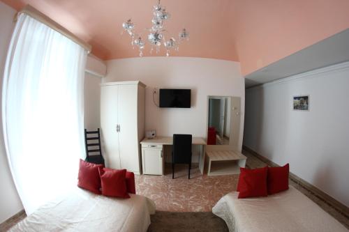 1 dormitorio con 2 camas con almohadas rojas y escritorio en Gualtiero Camere & Suite, en Caltagirone