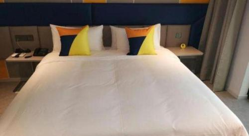 a large white bed with yellow and blue pillows at 7 Days Inn Guangrao Bus Station in Dongying