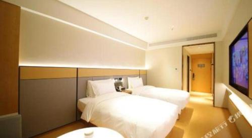 a bedroom with two beds and a flat screen tv at 7 Days Premium Chongqing Longtou Temple North Railway Station Center in Chongqing