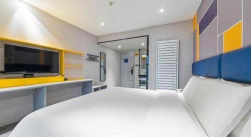 a bedroom with a large white bed and a tv at 7 Days Inn Guangrao Bus Station in Dongying