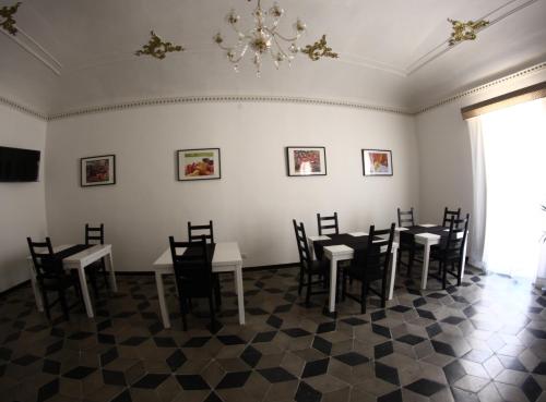 una sala da pranzo con tavoli, sedie e lampadario a braccio di Gualtiero Camere & Suite a Caltagirone