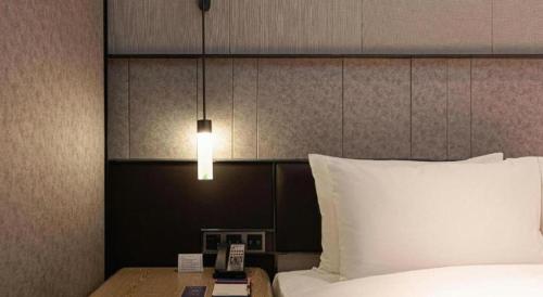 a bedroom with a bed and a nightstand with a lamp at Ethos Hotel Wuhan Riverside in Wuhan