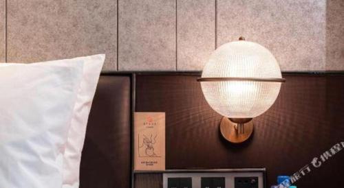 a lamp on a wall next to a bed at Ethos Hotel Wuhan Riverside in Wuhan