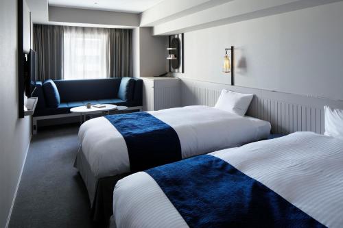 a hotel room with two beds and a couch at HOTEL TORIFITO KANAZAWA in Kanazawa