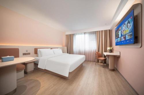 una camera d'albergo con un letto bianco e una scrivania di Hanting Hotel Zhangjiajie Tianmen Mountain Zhongshang Plaza a Zhangjiajie