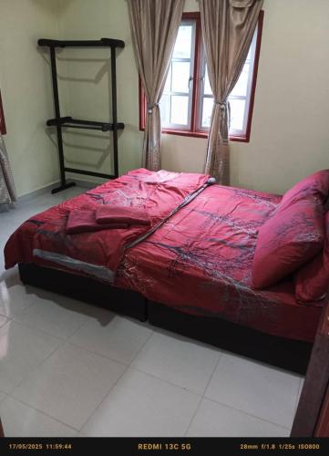a bed with a red comforter in a bedroom at My Guesthouse Bayas in Langkawi Intl