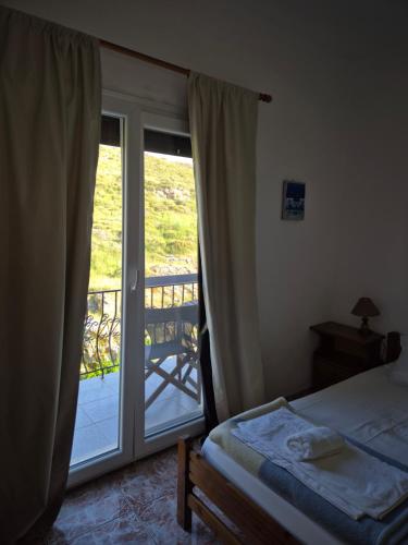 a bedroom with a bed and a sliding glass door at Kostas Studios Apartments - Ενοικιαζόμενα δωμάτια με κουζινάκι in Myrina