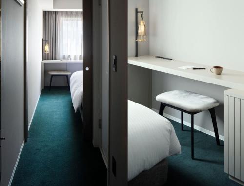 a hotel room with two beds and a desk and a chair at HOTEL TORIFITO KANAZAWA in Kanazawa