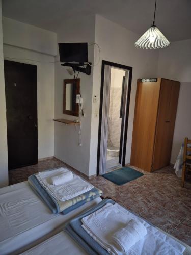 a room with two beds and a television and a door at Kostas Studios Apartments - Ενοικιαζόμενα δωμάτια με κουζινάκι in Myrina