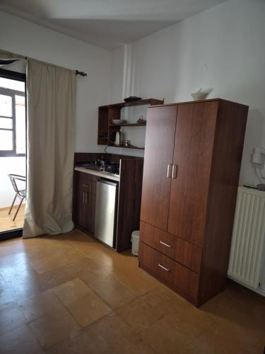 a kitchen with a large wooden cabinet in a room at Kostas Studios Apartments - Ενοικιαζόμενα δωμάτια με κουζινάκι in Mirina
