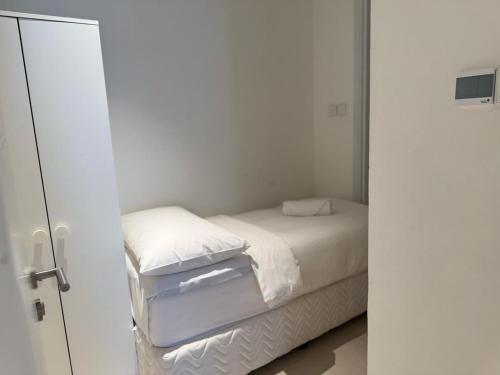 a bedroom with a bed with white sheets and pillows at Address Beach Resort Fujairah Apartment by Blue World - 4 in Fujairah