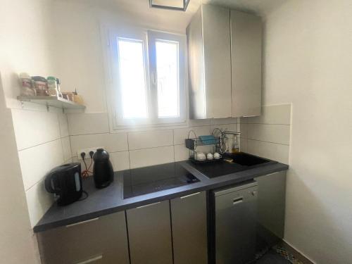 une petite cuisine avec un évier et une fenêtre dans l'établissement Gare saint Roch, à Montpellier