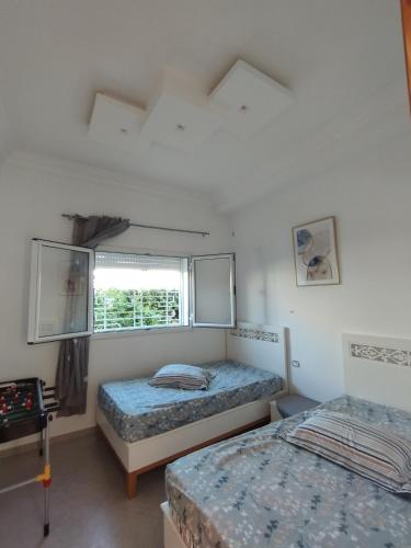 een slaapkamer met twee bedden en een raam bij Maison kelibia Ezzahra plage a pied in Ḩammām al Ghazzāz