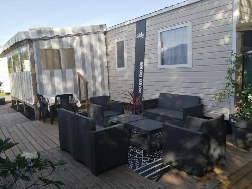 una casa y un patio con sillas y mesas. en Mobil home Menanteau, en Les Mathes