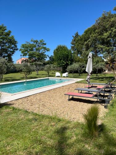 a swimming pool with an umbrella and two picnic tables at L'Atelier de la Baronnie - Lubéron in Cabrières-dʼAvignon