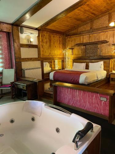 a bathroom with a bed and a tub in a room at Pineland Hotel and Health Resort in Ḩammānā