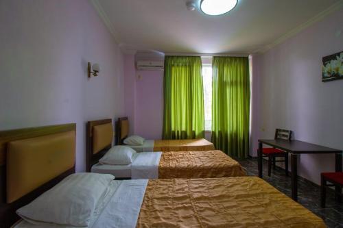 a room with two beds and a desk and green curtains at Golden Fleece Hotel in Ureki