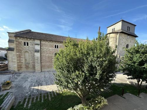 une ancienne église en pierre avec un arbre devant elle dans l'établissement Studio cosy face à l'église, à Le Mas-dʼAgenais
