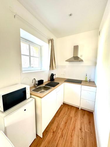 une petite cuisine avec des armoires blanches et un évier dans l'établissement Studio cosy face à l'église, à Le Mas-dʼAgenais