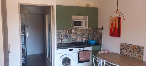 une cuisine avec un lave-linge et un micro-ondes dans l'établissement Le Paradis c'est ici, à Six-Fours-les-Plages
