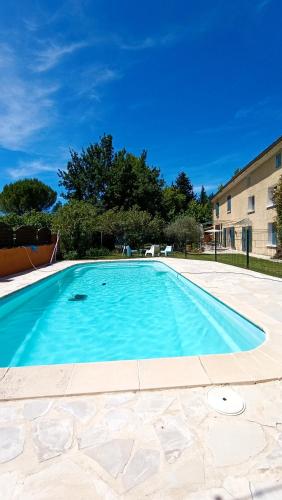une grande piscine bleue devant un immeuble dans l'établissement Mas de la Grave, à Althen-des-Paluds