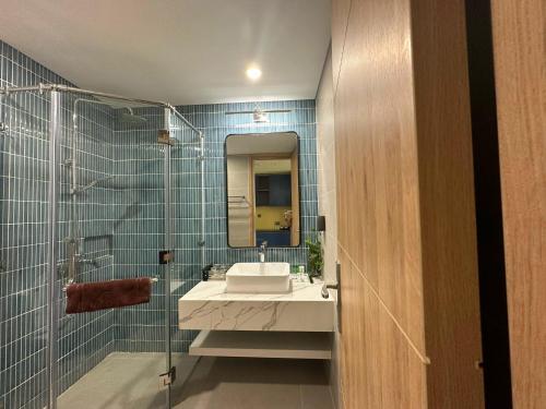 a bathroom with a sink and a glass shower at FLAMINGO Ibiza HaiTien - Ivy Abtel in Thanh Hóa