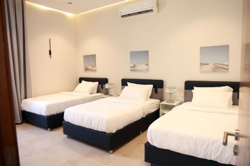 a room with two beds with white sheets at Wateera Jebel Sifah in As Sīfah