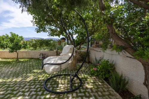 a white chair sitting under a tree in a yard at Allegro Apartment 2 in Lakithra