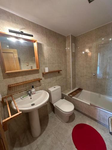 a bathroom with a toilet and a sink and a tub at La Isla Bonita in Daimuz