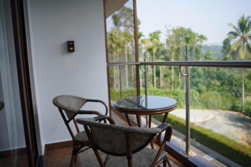 a balcony with two chairs and a table and a window at Saugandhika West Gate in Wayanad